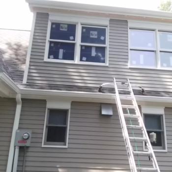 Exterior home repair in Miami with ladder for siding/window work. Miami handyman exterior work: ladder by siding and upstairs windows