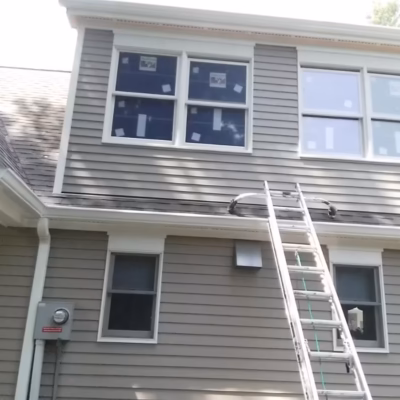 Exterior home repair in Miami with ladder for siding/window work. Miami handyman exterior work: ladder by siding and upstairs windows